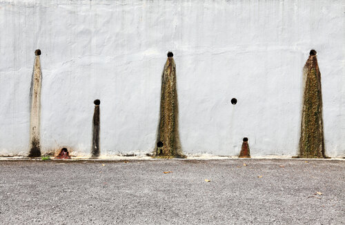 Weeping holes with slurry stain on a concrete retention wall. 