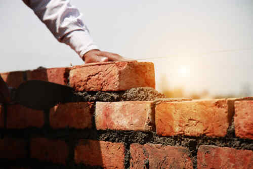 Mason installing brick on construction site for making house.     